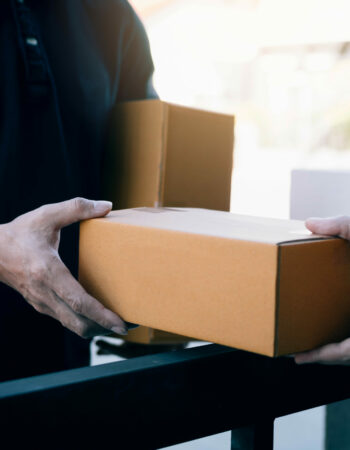 Close up of hands cargo staff are delivering cardboard boxes with parcels inside to the recipient's hand.